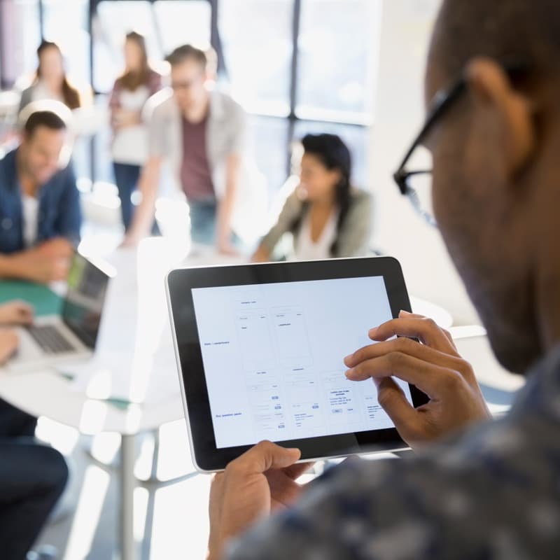 man working on tablet in an office with other working people