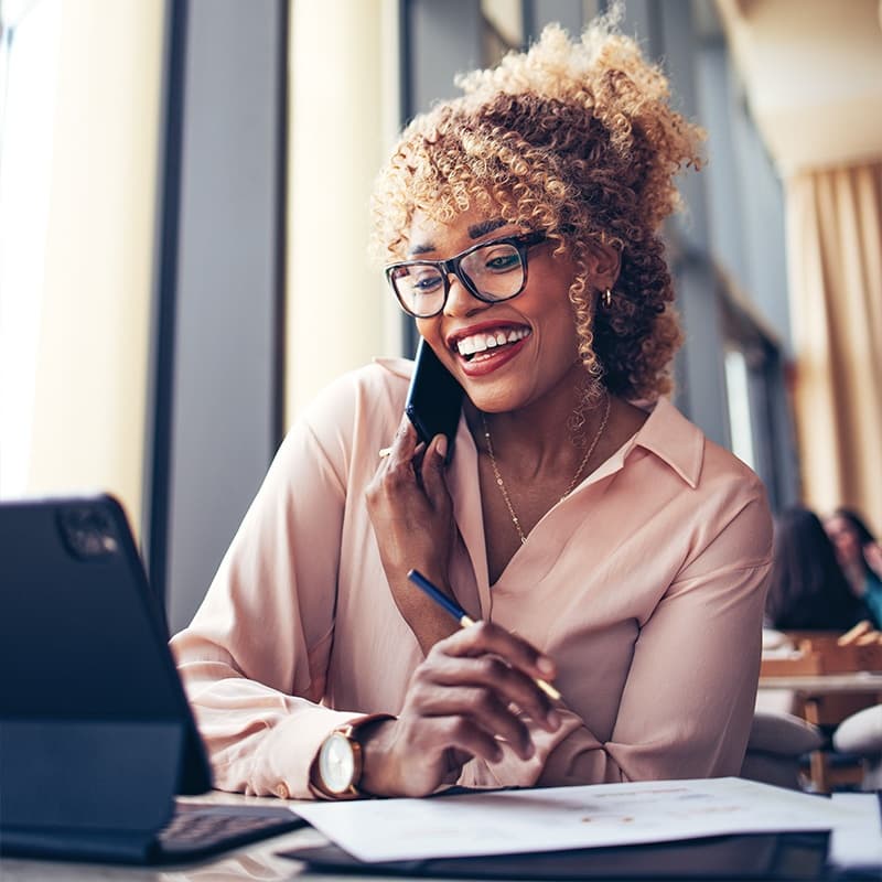 Businesswoman Talking On A Mobile Phone while working on laptop