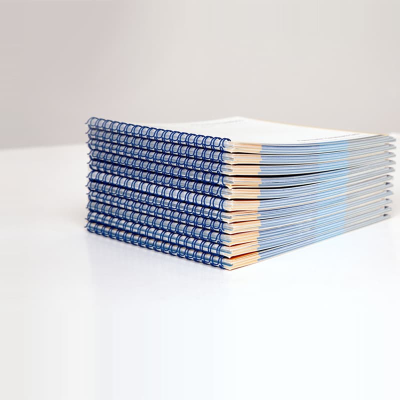 stack of booklets with blue wire-o binding on a table