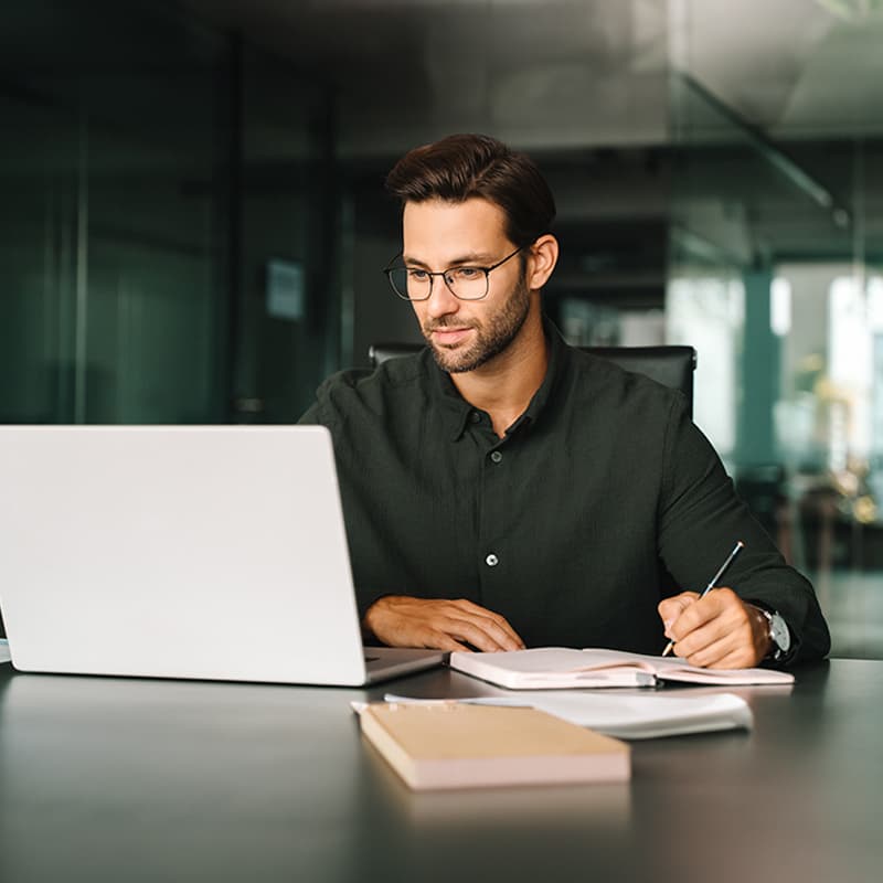 A professional working with a laptop and notebook, demonstrating career opportunities