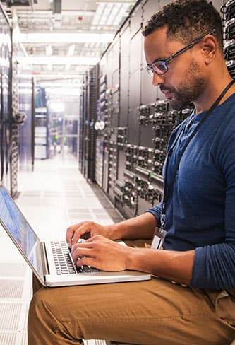 man on laptop in server room