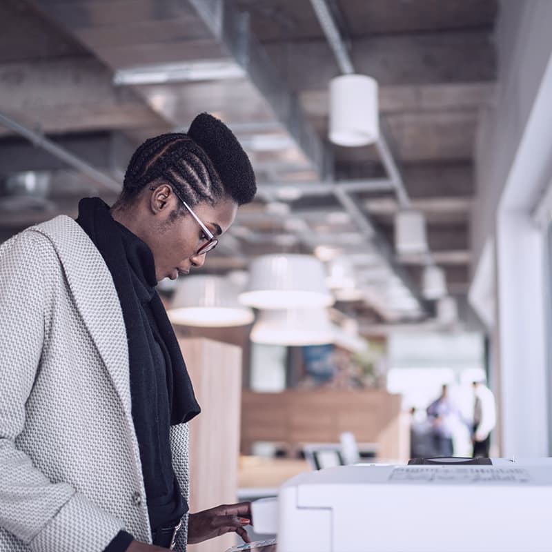 Young businesswoman using computer printer