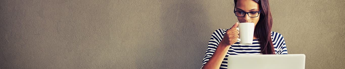 Woman drinking coffee and working on a laptop